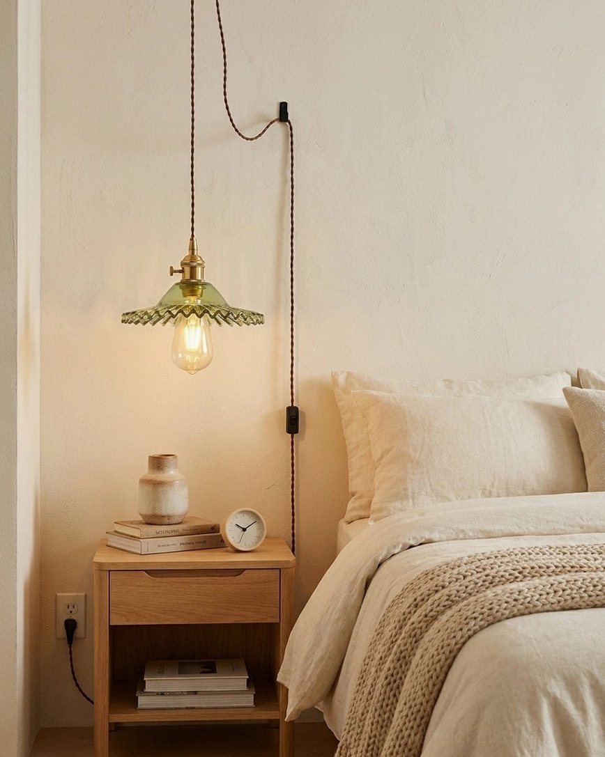 Vintage pendant light hanging above bedside table in bedroom, green fluted glass with brass hardware and warm ambient lighting
