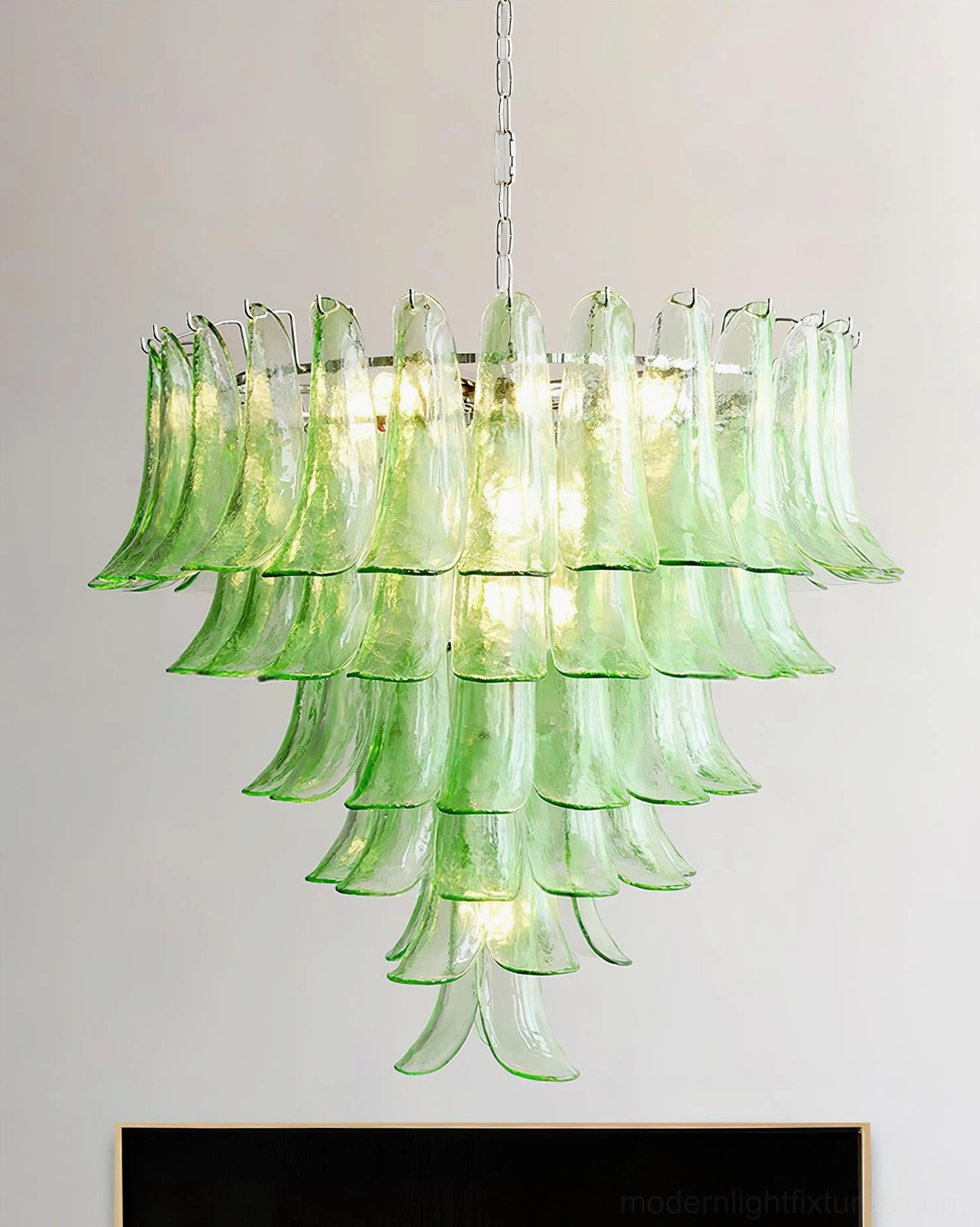 Green translucent glass petal chandelier in modern living room with fireplace and white trim
