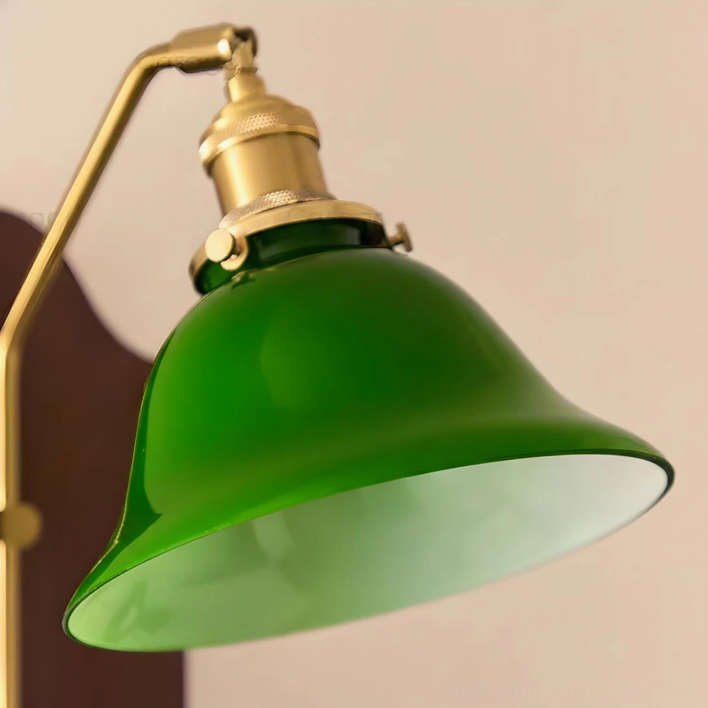 Green glass shade wall sconce unlit showing sculptural brass arm and natural wood backplate construction