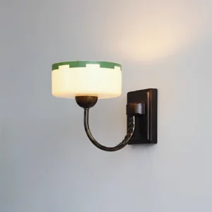 Green glass wall sconce mounted on gray wall with illuminated vintage design, Art Deco lighting fixture