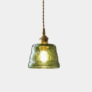 Green hammered glass pendant light with brass hardware and twisted fabric cord close-up