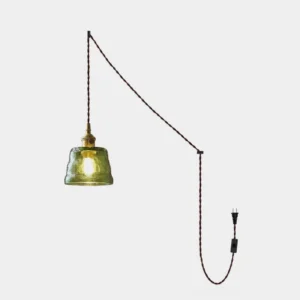 Molded glass plug-in pendant light with green shade and brass socket, front studio view on white background