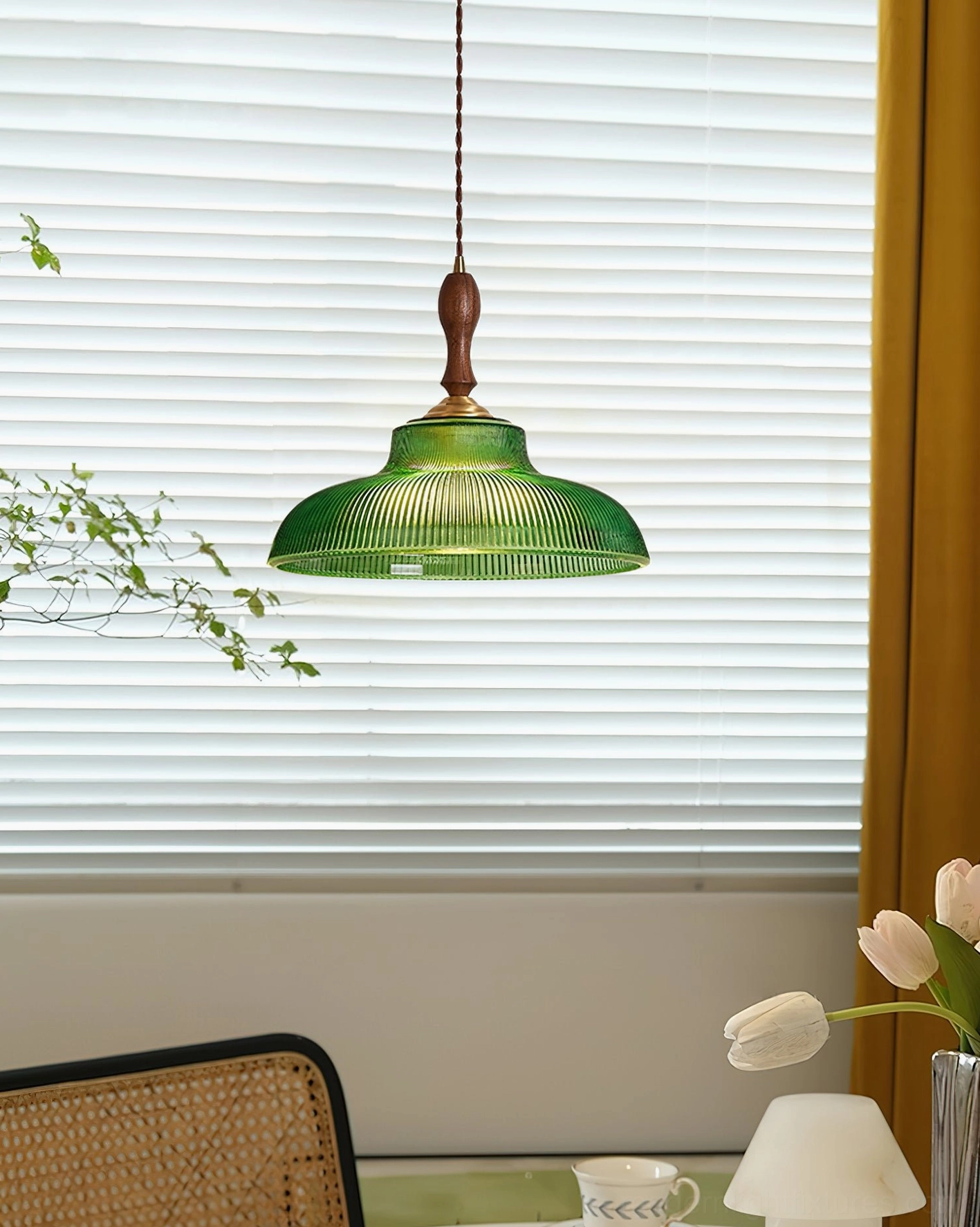Vintage green glass pendant light through window blinds creating warm ambient dining nook lighting