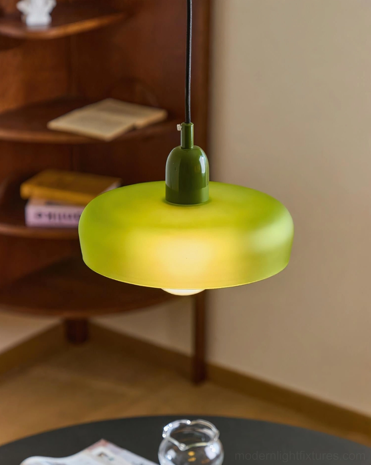 Green frosted glass donut pendant light low overhead view in vintage home dining area, showing retro minimalist style and warm ambient illumination