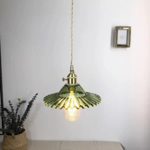 Green fluted glass pendant lamp illuminated in modern home interior with dried plant decoration and exposed edison bulb