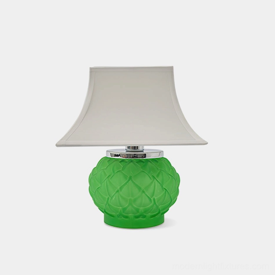 Green Petaluxe sculptural table lamp with textured green glass petal-inspired base and white fabric shade, studio front view