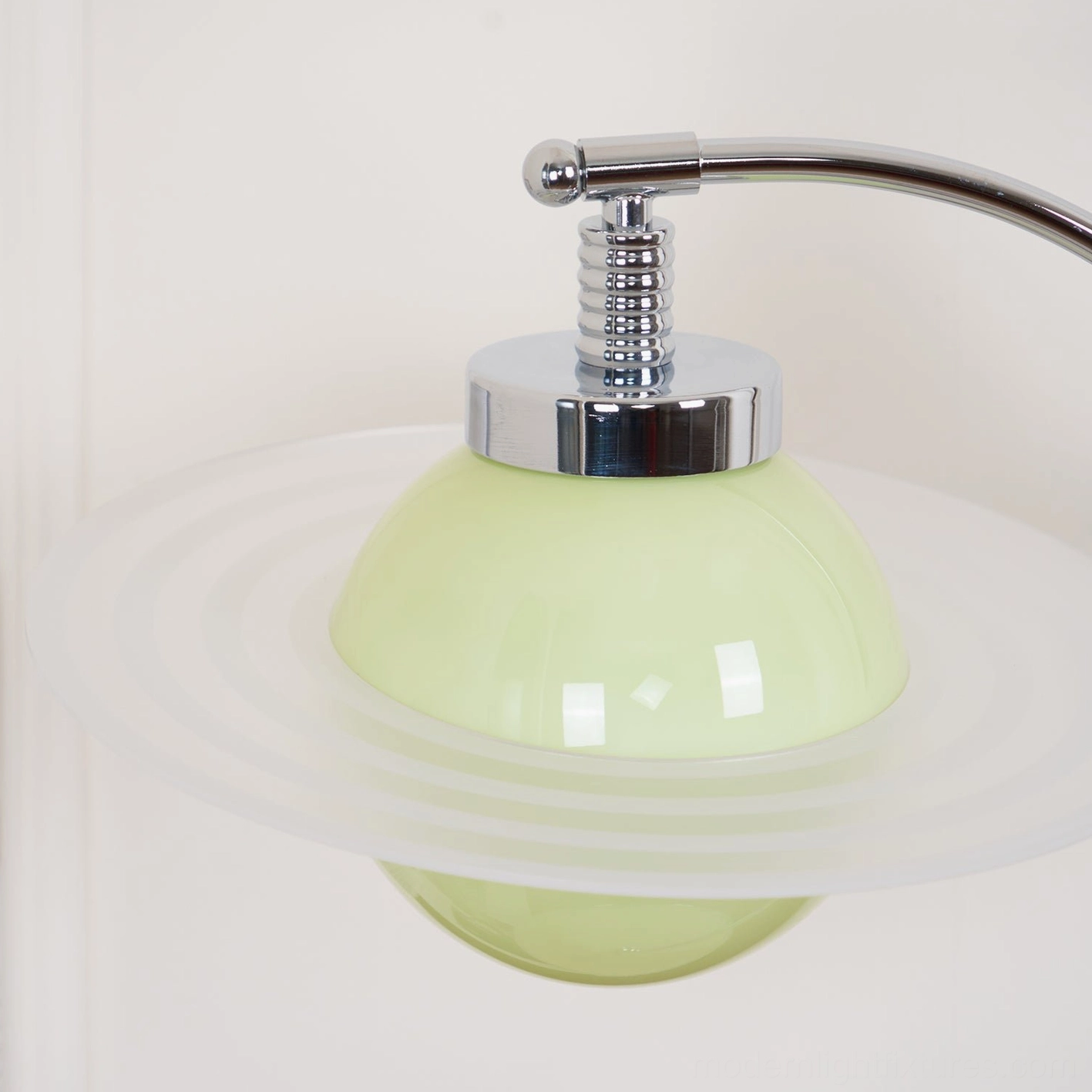 Close-up detail of green glass sphere with frosted transparent glass ring fixture and polished chrome hardware