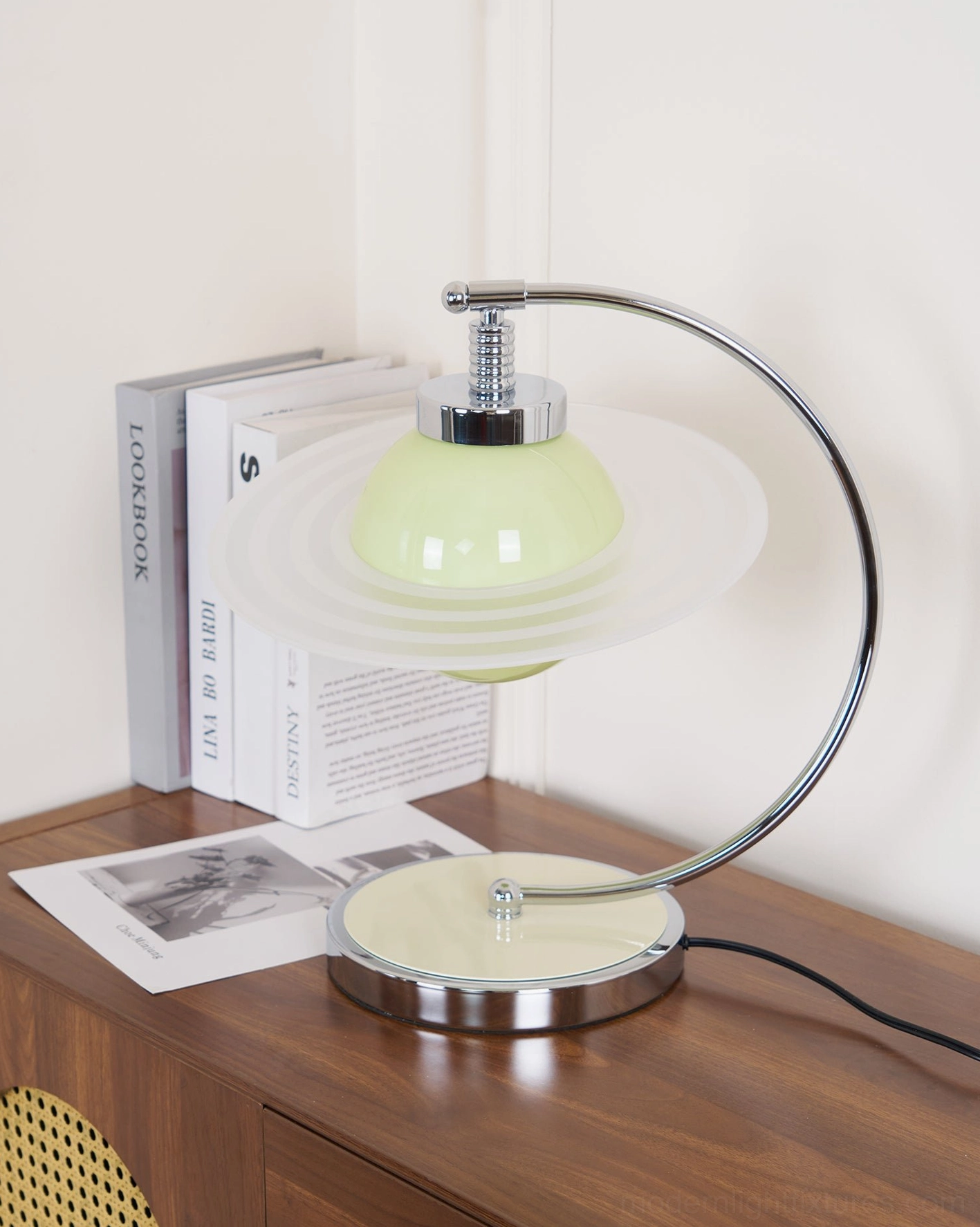 Modern green table lamp positioned on minimalist home cabinet with perforated front panel design