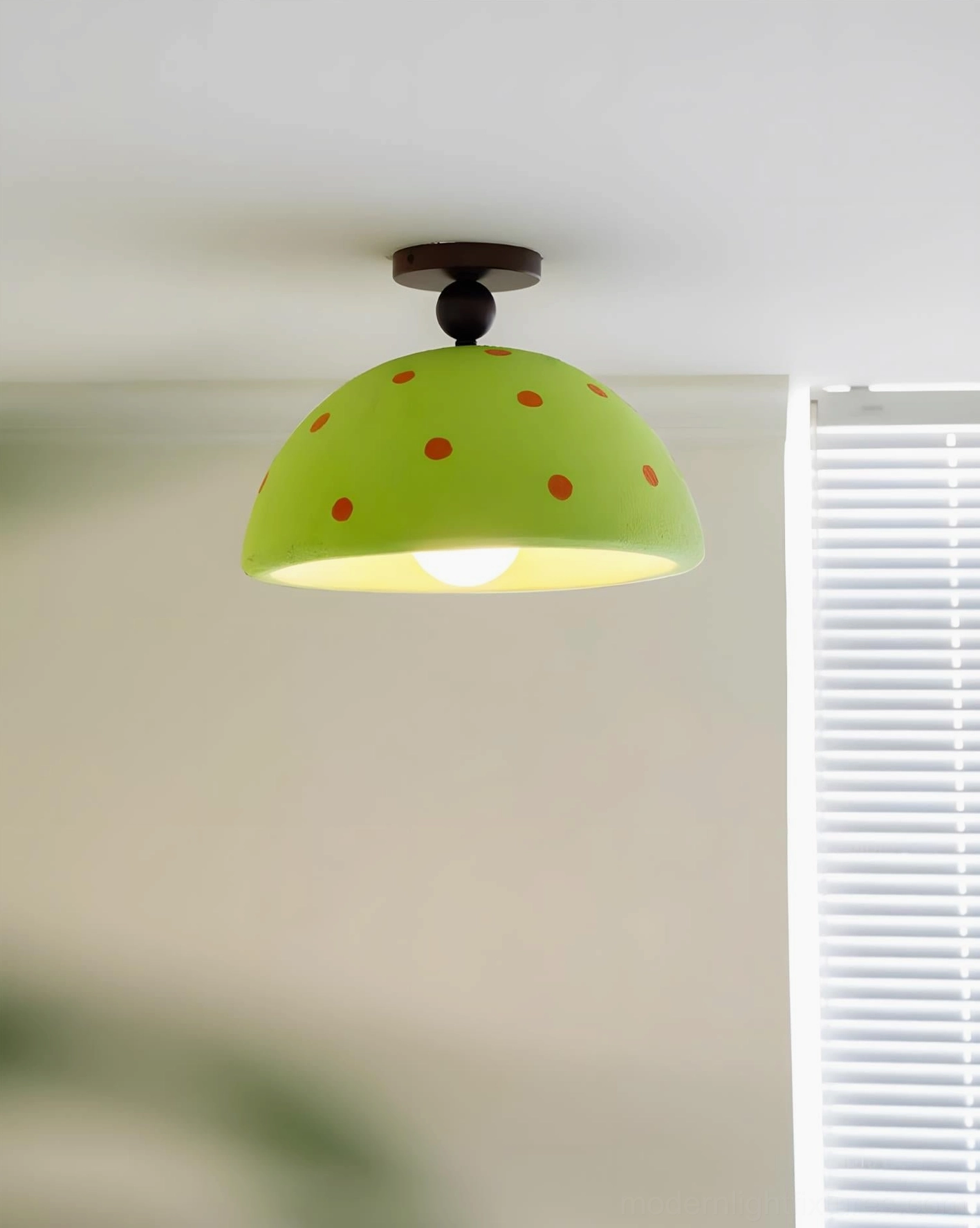 Lime green polka dot ceiling light with exposed bulb near window with modern blinds