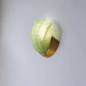 Green translucent shell wall sconce mounted on wall - side illuminated view showing light diffusion