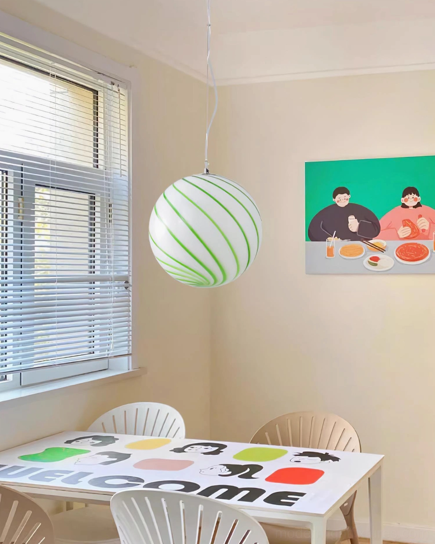 Green spiral stripe glass pendant light hanging in modern children's dining room creating warm ambient lighting above the table