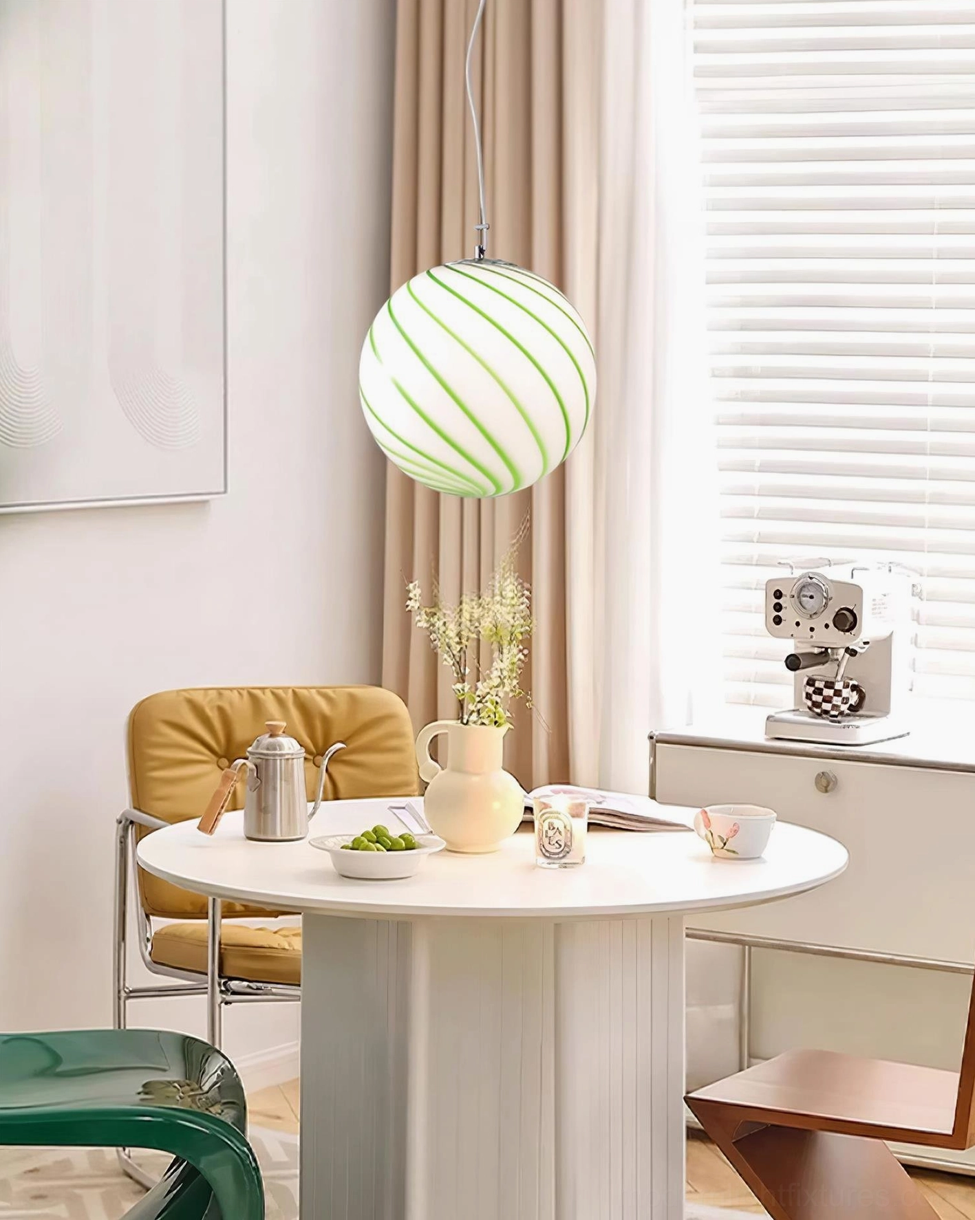 Green spiral stripe glass pendant light installation above white round dining table in contemporary home interior space