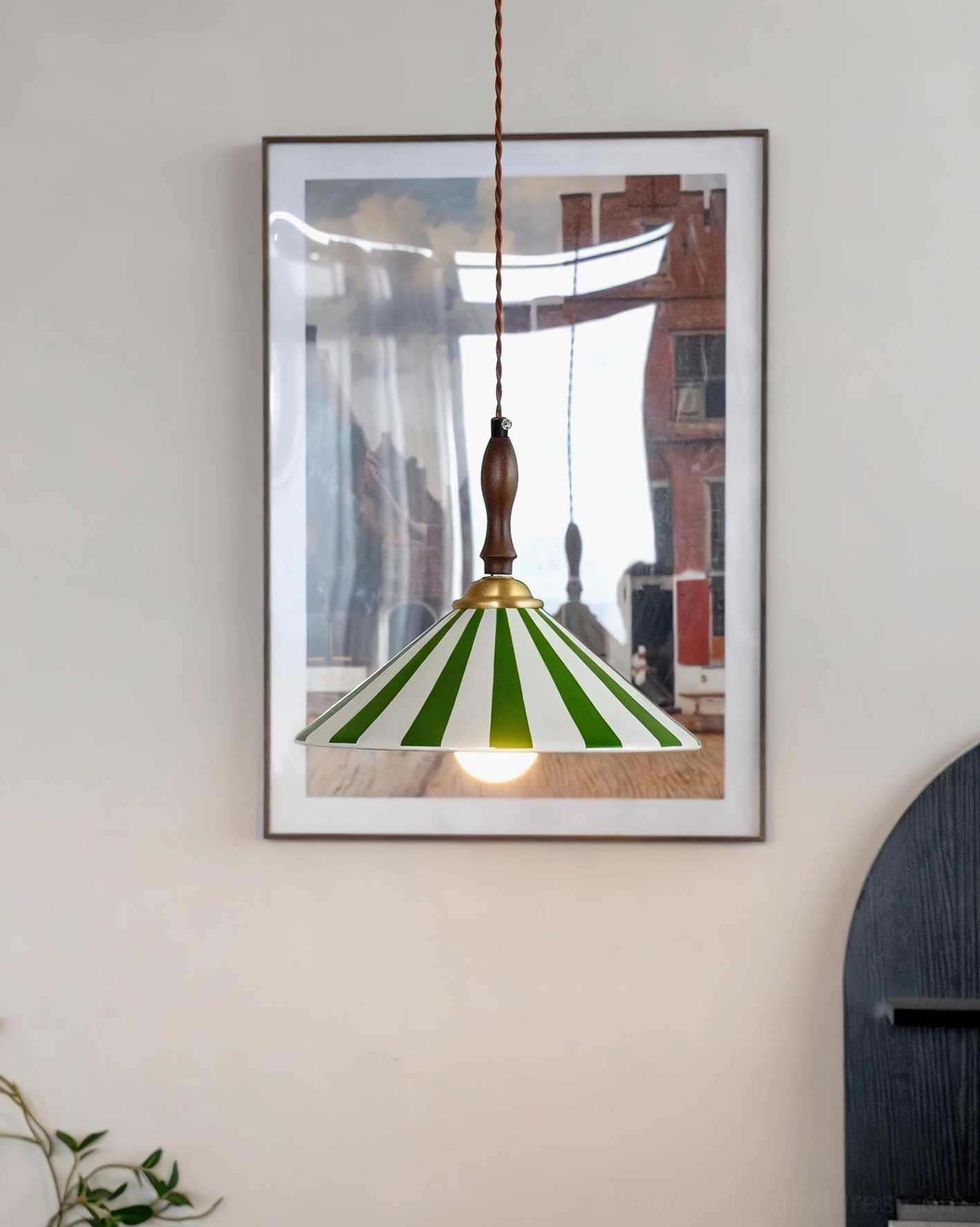 Green and white striped hand-painted ceramic pendant lamp with warm glowing exposed bulb in cozy home interior setting with wall art