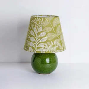 Close-up of green table lamp showing detailed leaf pattern fabric shade and glazed ceramic base