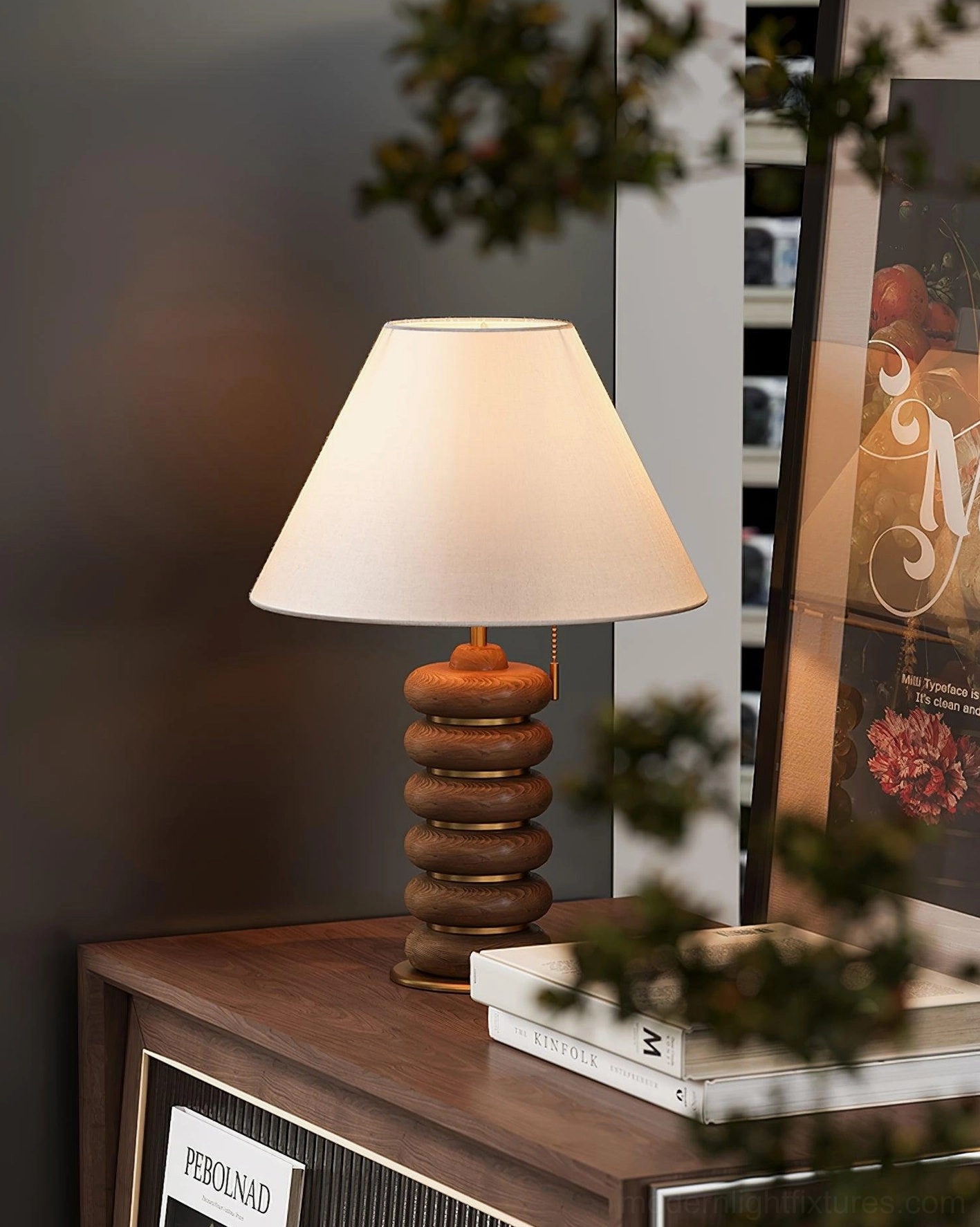 Walnut stacked wood table lamp indoor side table display with blurred green plant foreground
