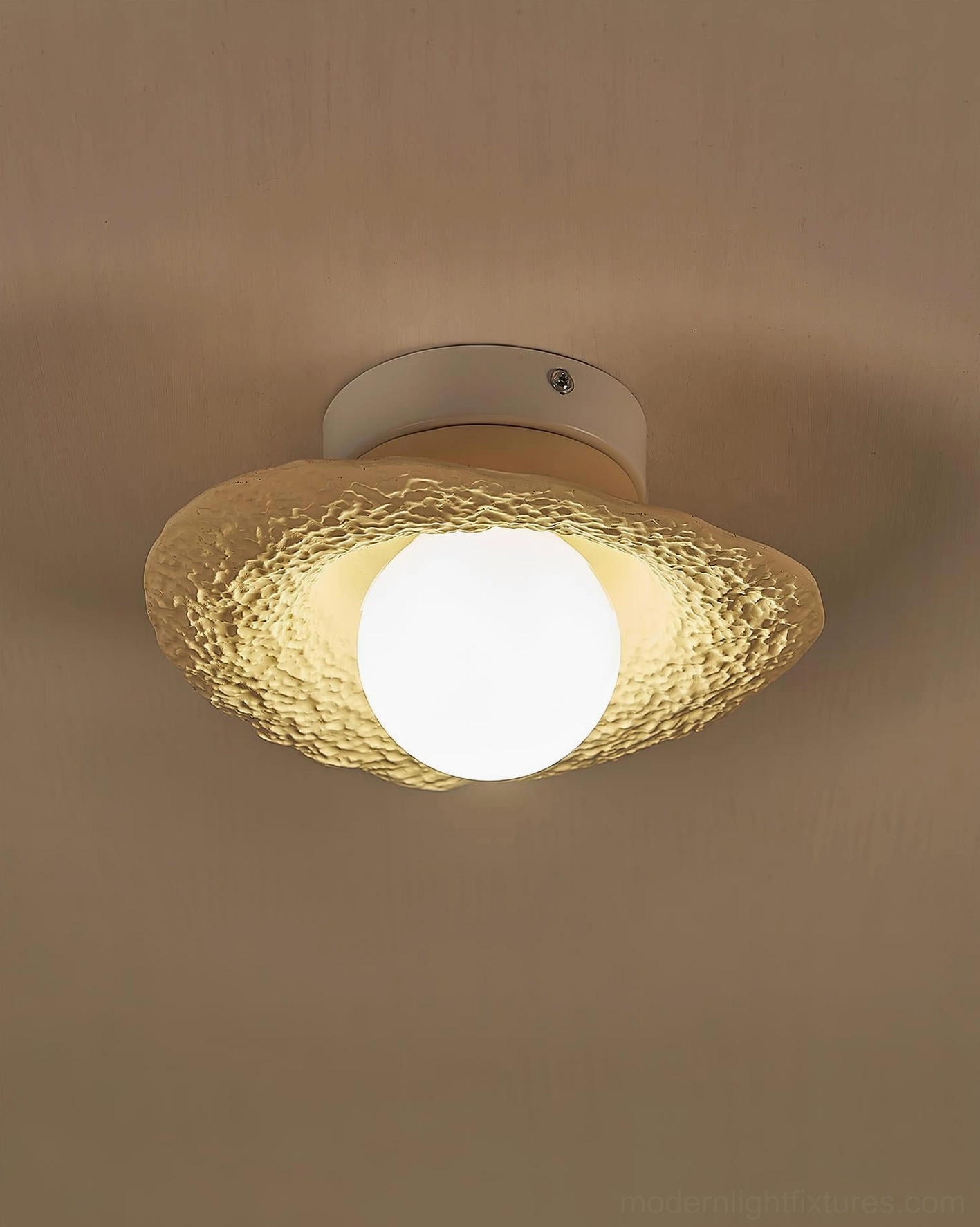 Grima textured hat pendant lamp with amber rough finish and glowing central spherical bulb, close-up view