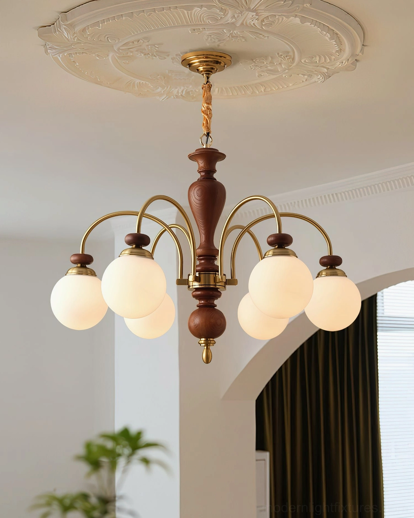 Guillerme 8-head wooden chandelier with dark brown frame and brass accents in arched entryway dining space