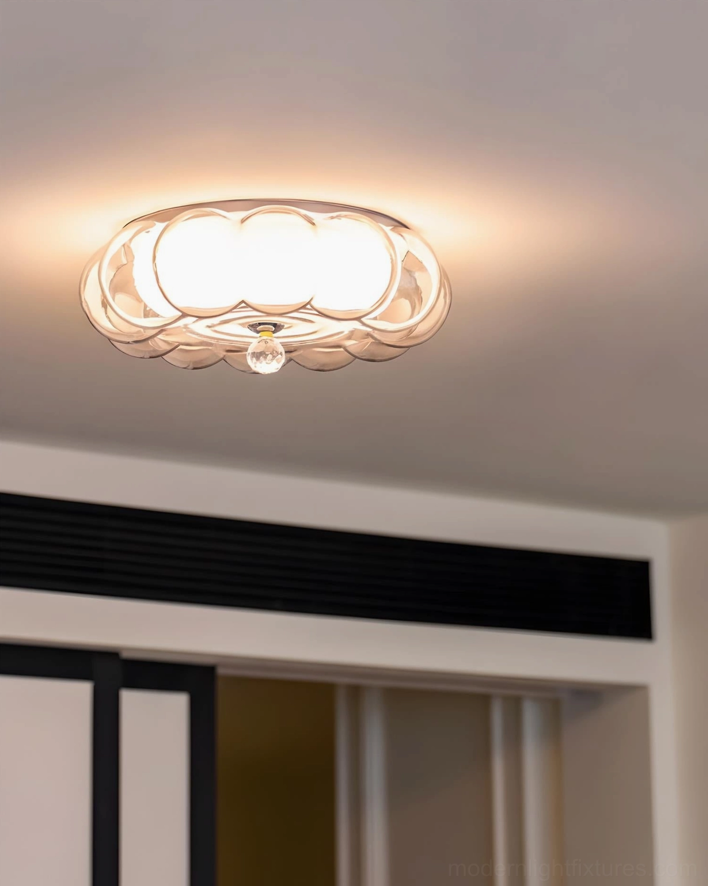Cream white glass ceiling light with warm illuminated glow, upward viewing angle, floral glass shade detail in residential setting