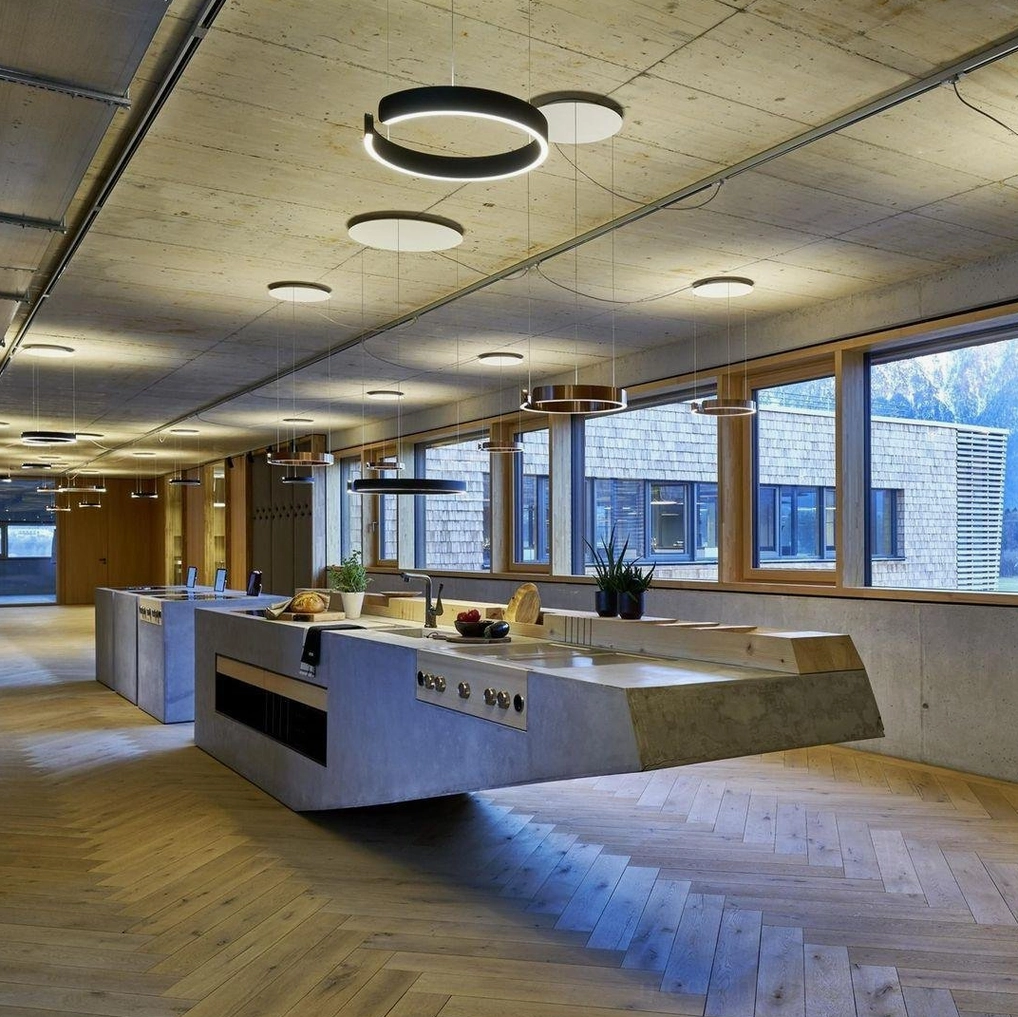 Ring-shaped LED ceiling lights in modern open office kitchen with black and white finishes, overhead view