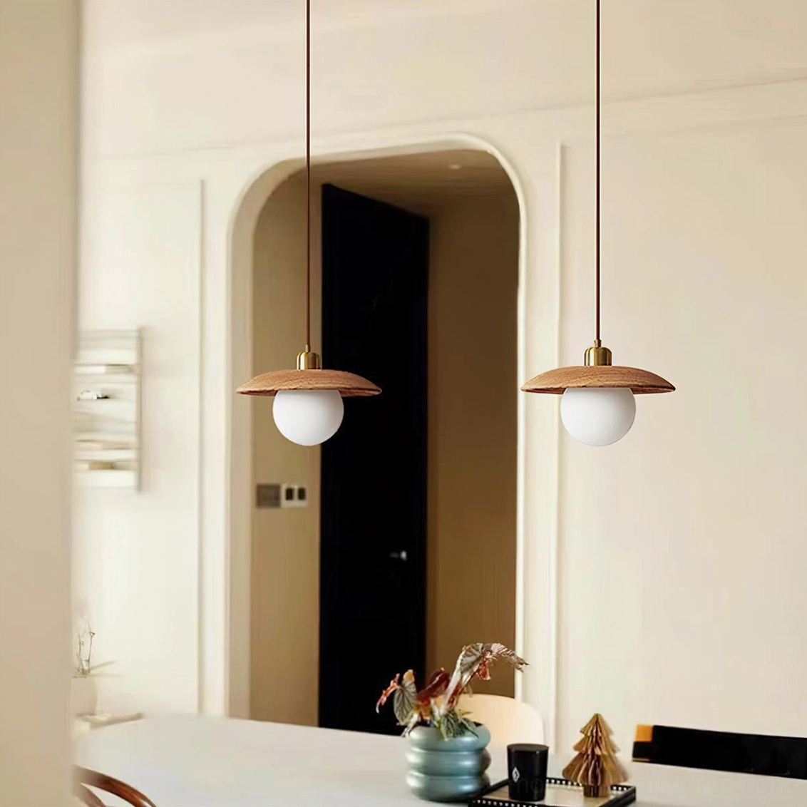 Modern oak pendant light installed in residential dining room above wooden table with warm ambient lighting