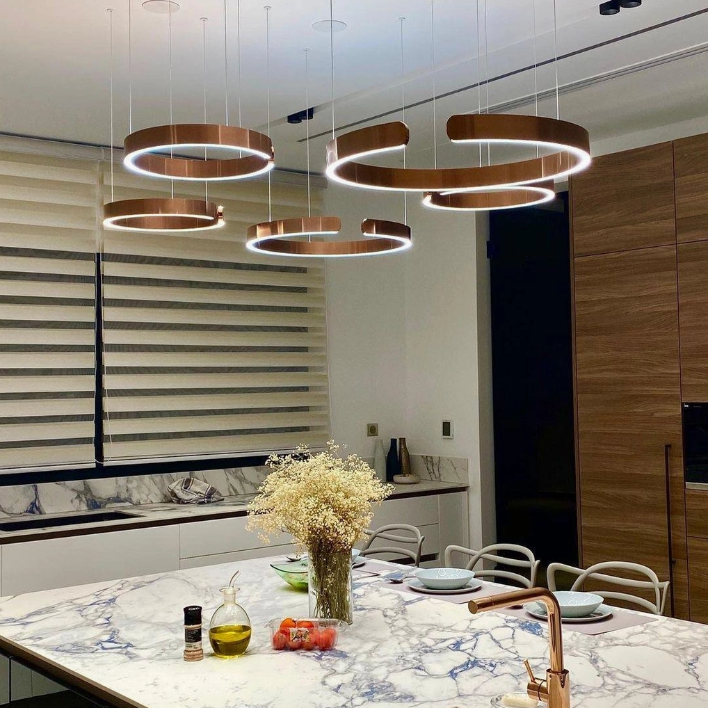 Multiple rose gold halo ring pendant lights installed in contemporary kitchen dining area with ambient warm lighting