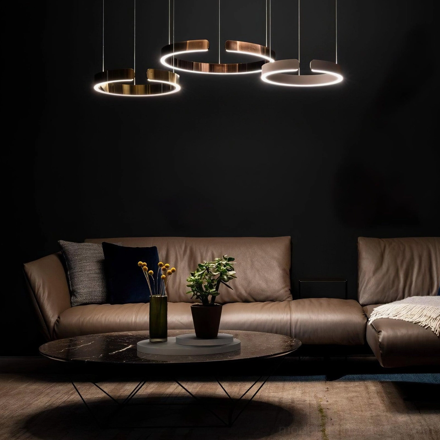 Multiple rose gold halo ring pendant lights illuminating modern living room with dark walls and leather sofa