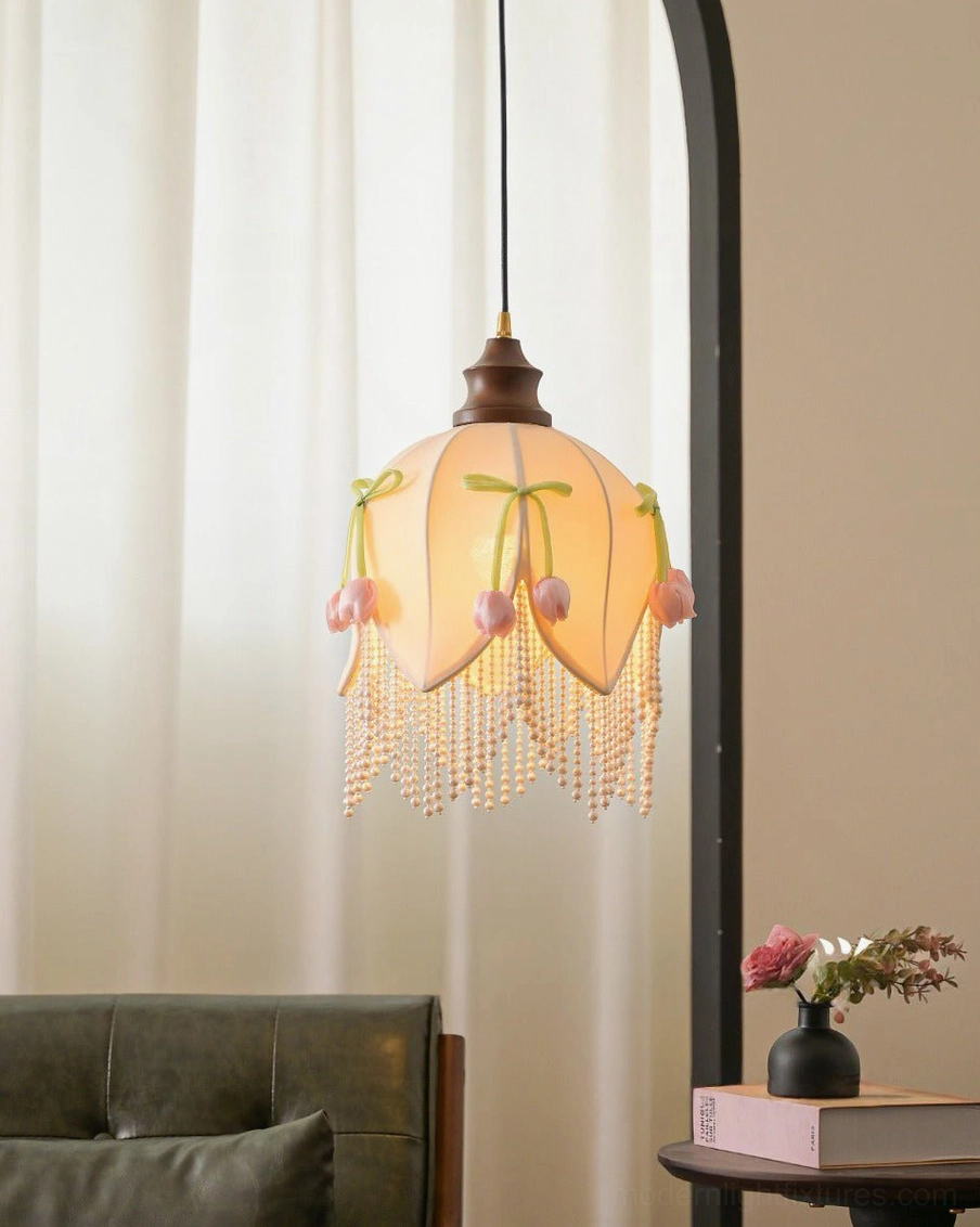 Hanavelle cream tulip pendant light front close-up view with warm light glow, detailed pearl-bead fringe and ash wood cap visible, curtain backdrop interior setting