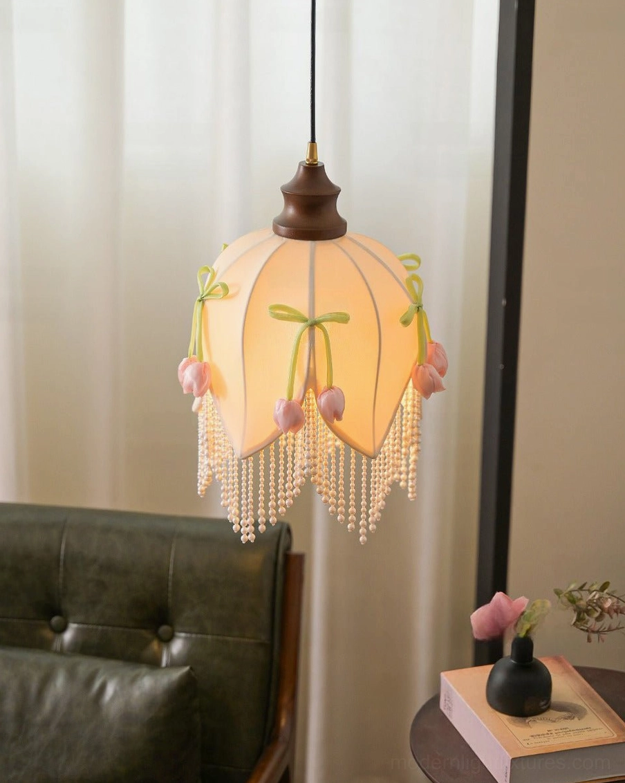 Hanavelle warm-glowing tulip pendant light in modern living room corner near dark leather sofa, close-up of illuminated cream fabric shade with pearl fringe, 2700K warm white ambiance