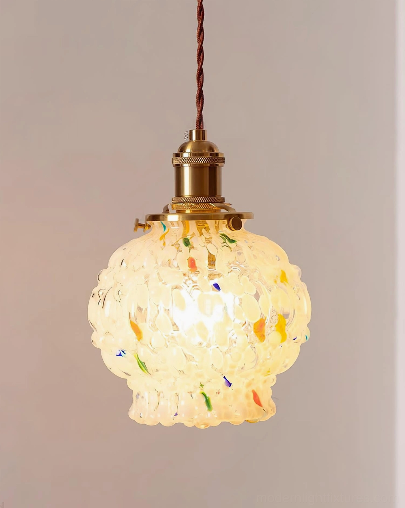 Close-up textured hand-blown frosted glass shade with colorful speckles, polished brass hardware detail, studio background