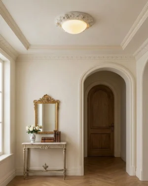 Hand-carved floral flush mount light installed in French country style entryway with gilded vanity mirror and herringbone flooring