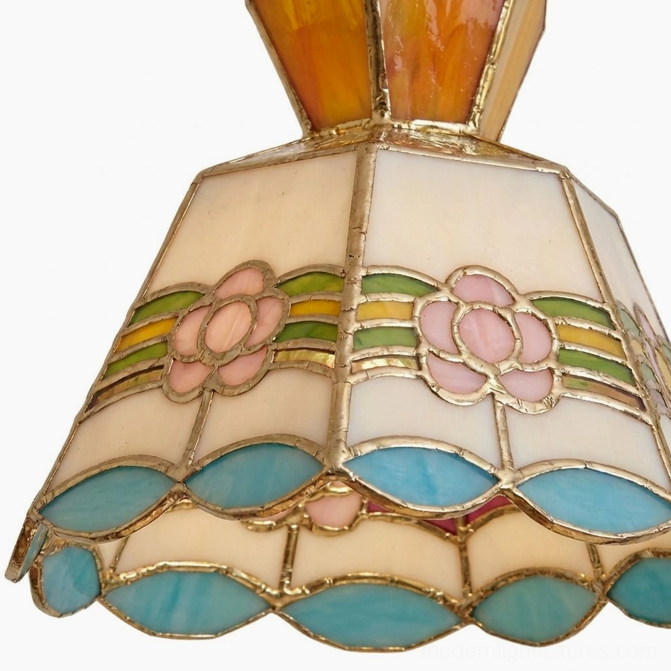 Close-up detail of hand-cut stained glass pendant shade showing individual colored glass panels with copper-foil soldered seams floral motif and brass trim