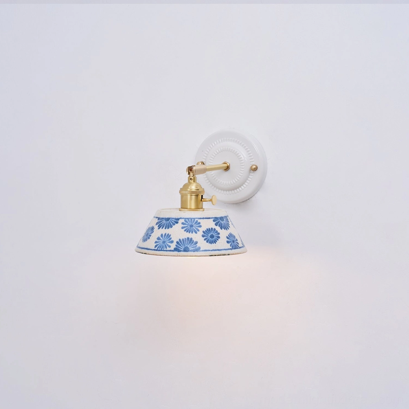 Hand-glazed indigo porcelain wall sconce with brass arm and white ceramic backplate