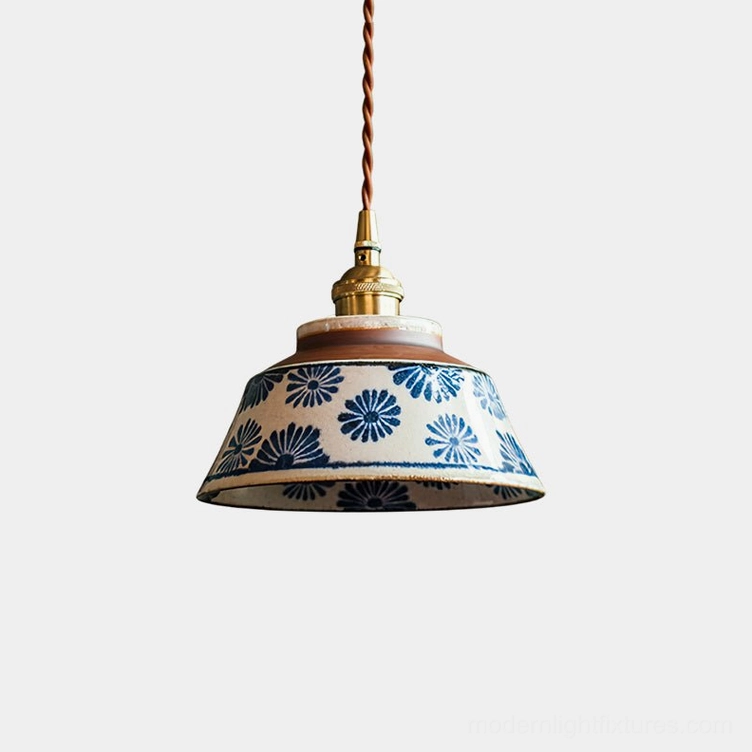 Hand-painted ceramic pendant light with blue floral pattern, brass fittings, and twisted cord on white background
