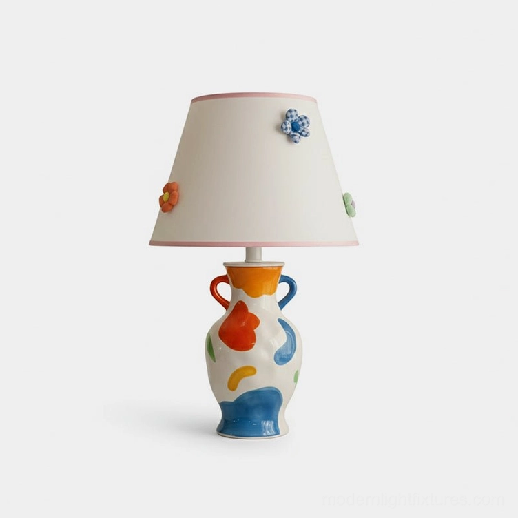 Hand-painted ceramic table lamp with multicolor abstract base and white fabric shade trimmed in soft pink with 3D floral accents, frontal studio view