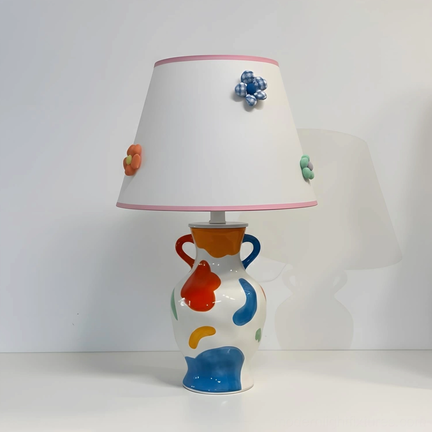 Hand-painted ceramic table lamp with multicolor abstract painted base and soft pink trimmed white fabric shade with 3D ceramic flowers