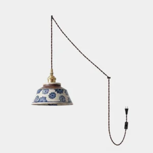 Hand-painted indigo ceramic plug-in pendant lamp with chrysanthemum pattern on warm cream stoneware, brass socket, and twisted braided cord on white background