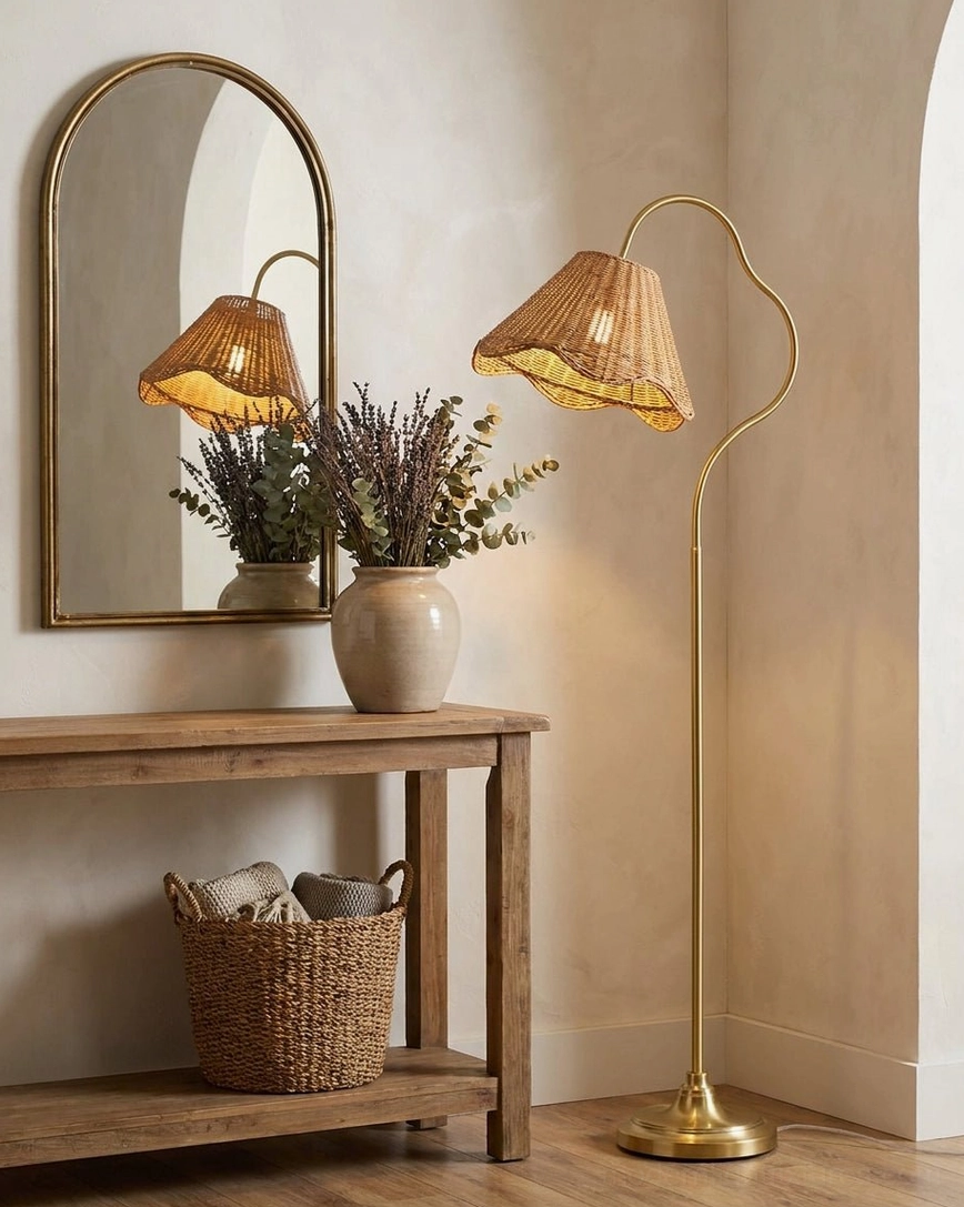 Rattan arc floor lamp in warm gold finish positioned in entryway beside arched mirror and wooden console table