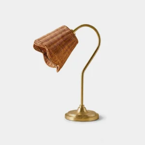 Hand-woven rattan table lamp with warm gold gooseneck arm and scalloped shade on studio background