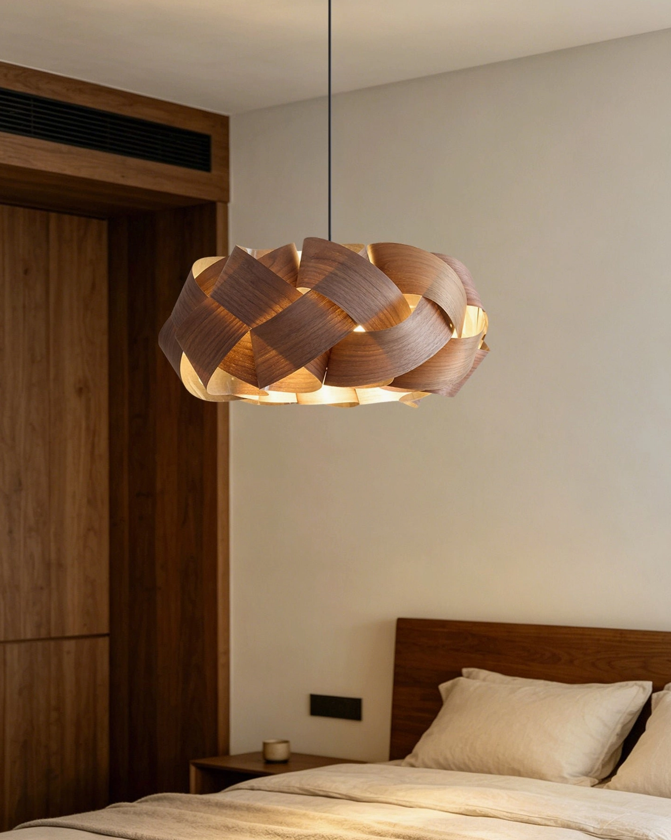 Hand-woven walnut wood pendant light in minimalist bedroom entry with wooden door and warm lighting