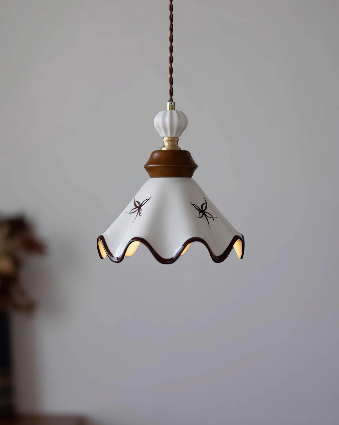 Close-up detail of handcrafted ceramic scalloped pendant light showing brown hand-painted decoration and edge work