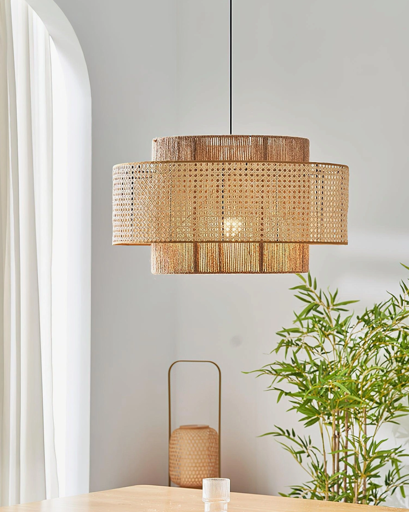 Handcrafted rattan weaving pendant light hanging above dining table with potted plant, boho dining room interior styling