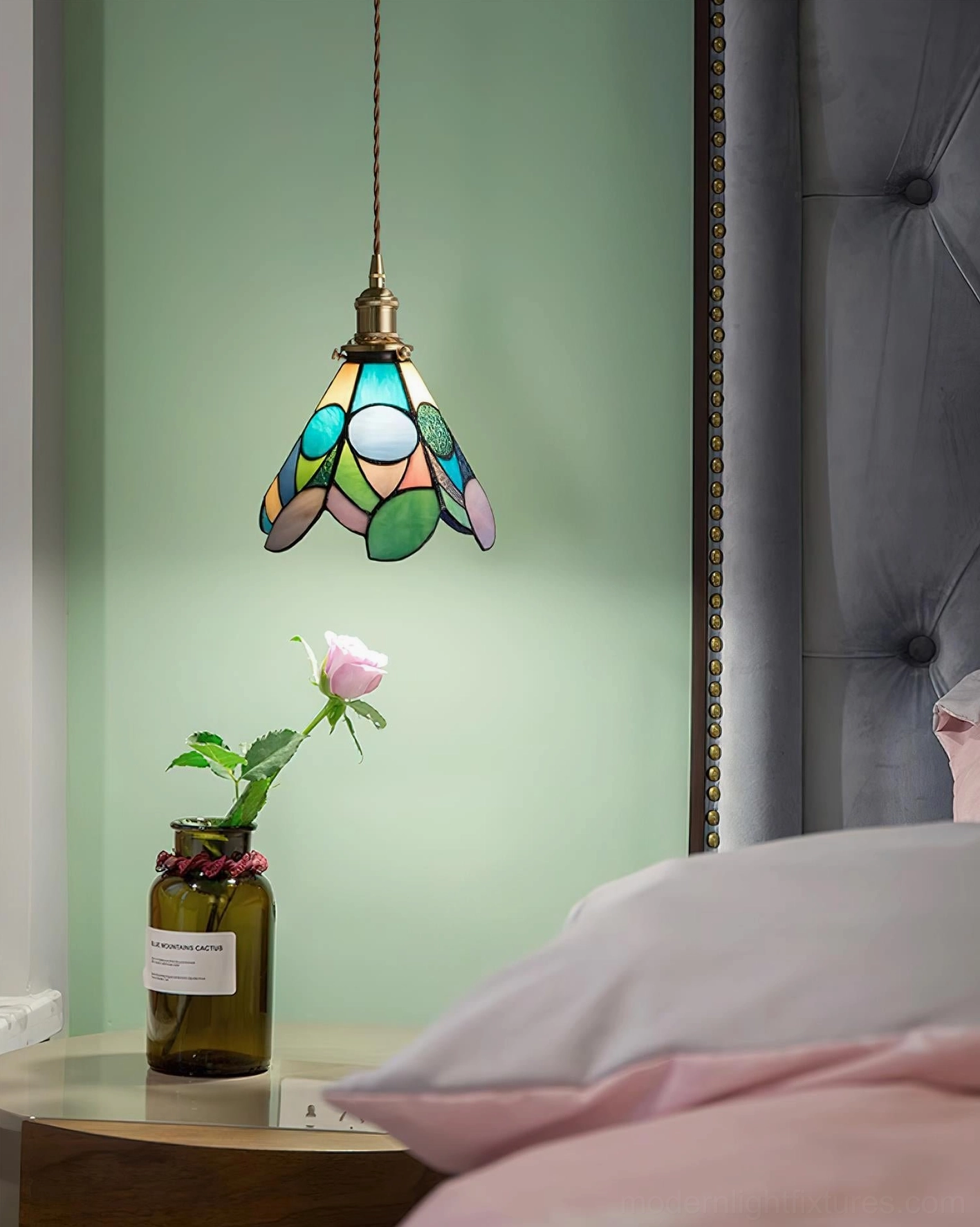 Handcrafted stained glass pendant lamp showing intricate floral patterns in warm light with brass hardware