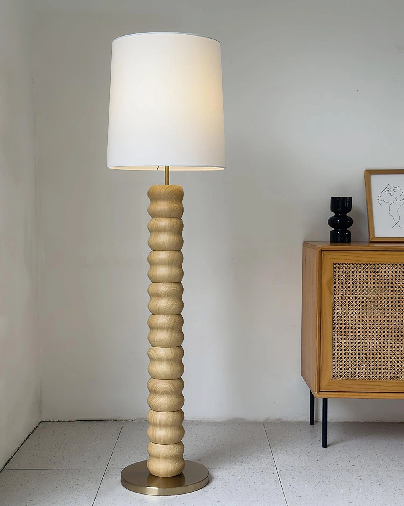 Handcrafted wooden stacked floor lamp with natural grain texture and brass base under ambient lighting