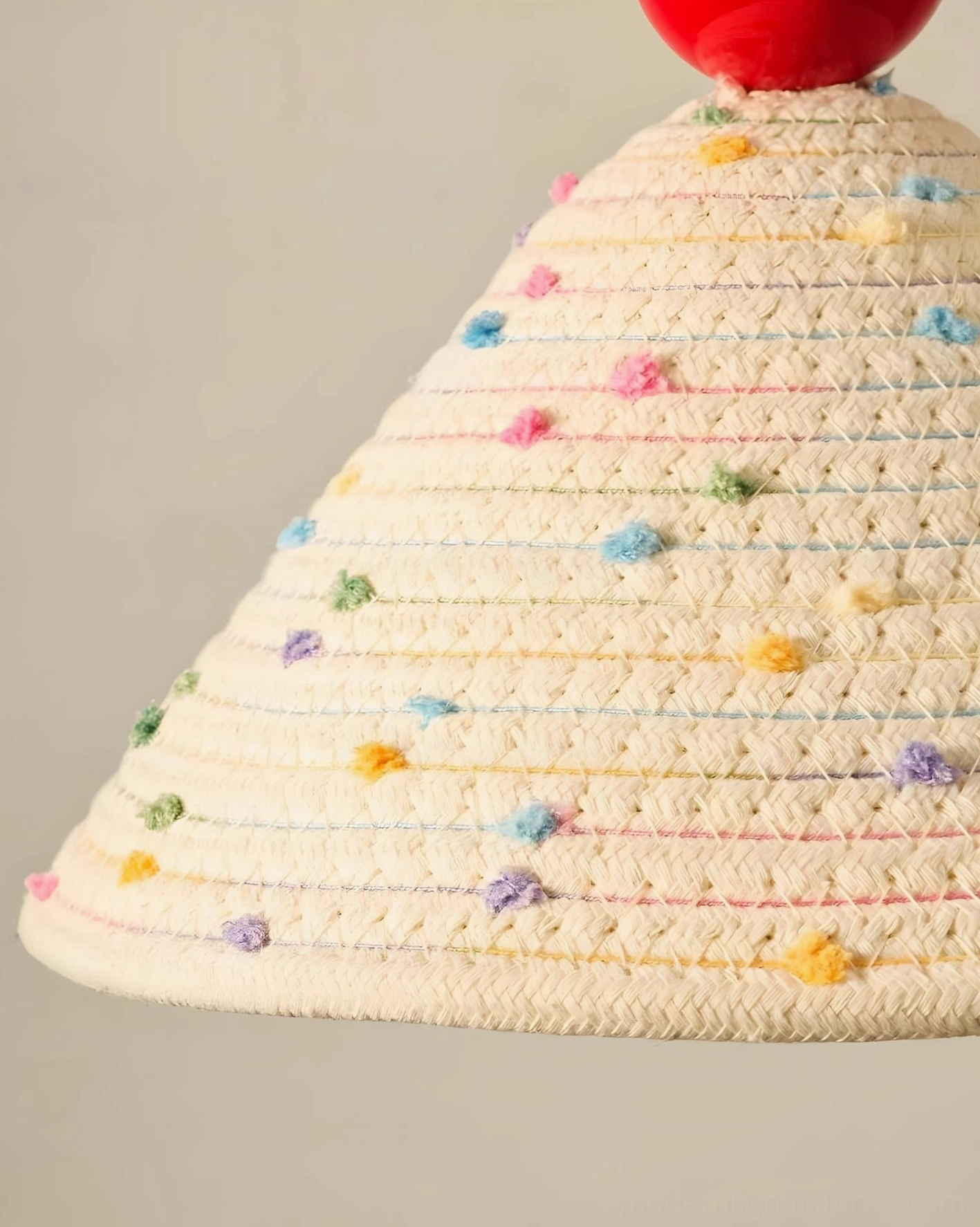Close-up detail of hand-woven cotton fabric shade with colorful pom-pom trim and textile texture