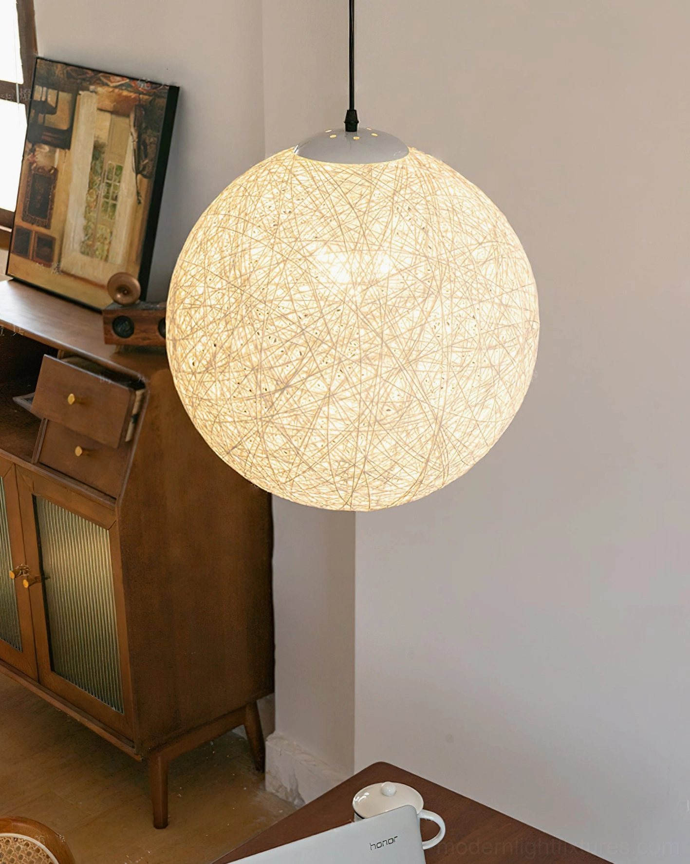 Off-white handwoven hemp pendant light styled in vintage interior corner with wooden cabinet, bohemian home decor setup