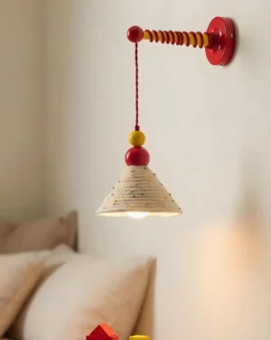 Colorful wall mounted sconce installed beside bedroom bedside table with red metal mount and sculptural bead detailing