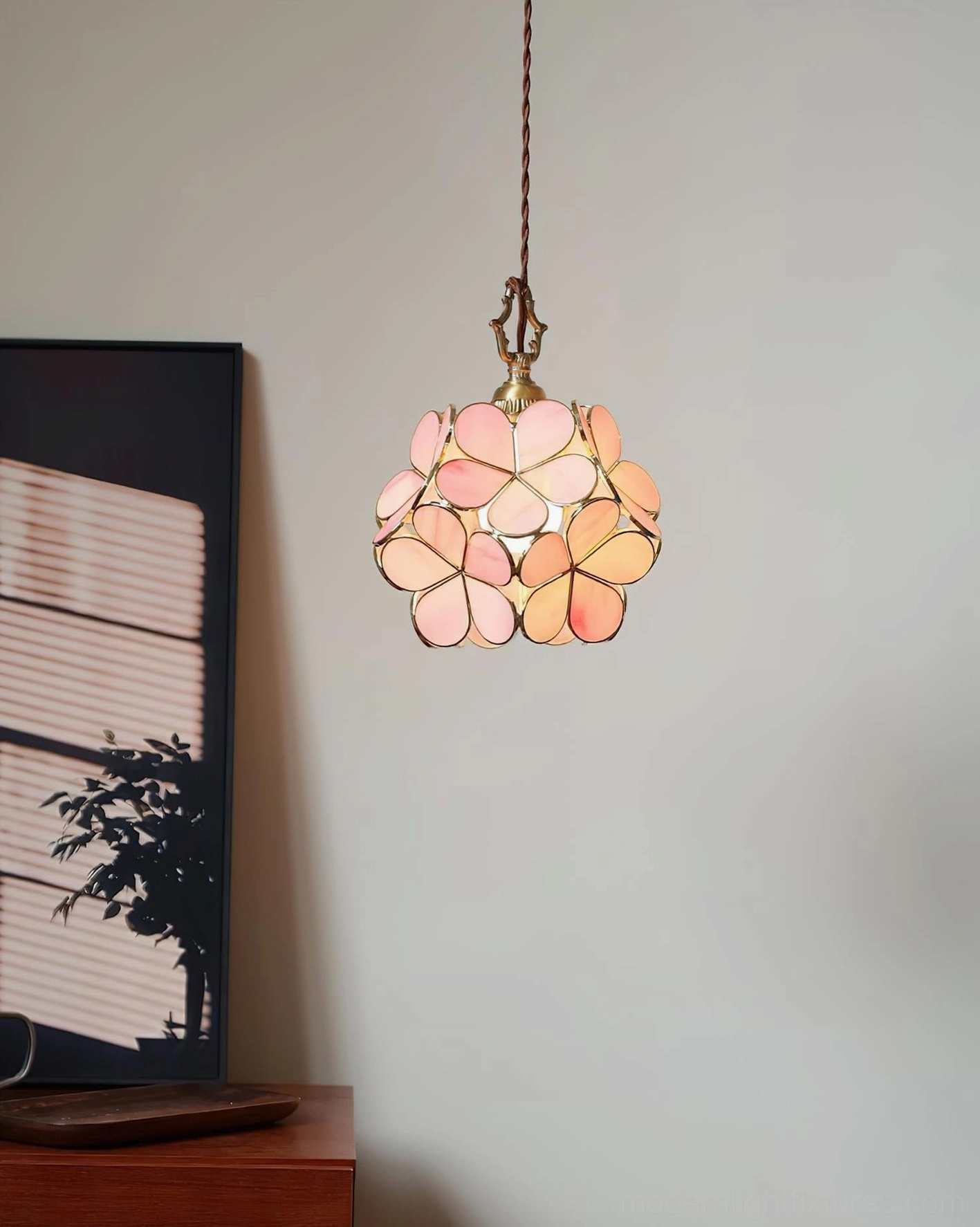 Illuminated pink glass flower pendant light creating warm glow above wooden side table