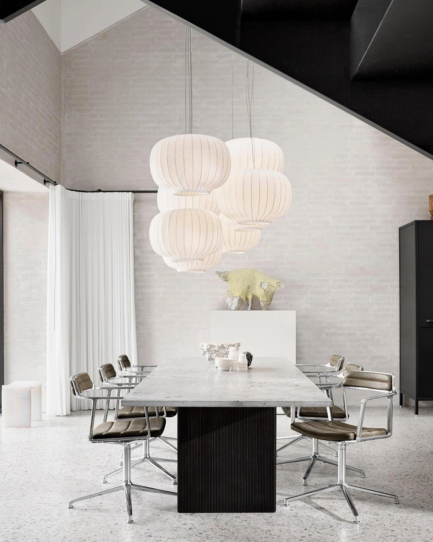 Multiple modern fabric pendant lights with off-white ribbed shades in high-ceiling dining and meeting room