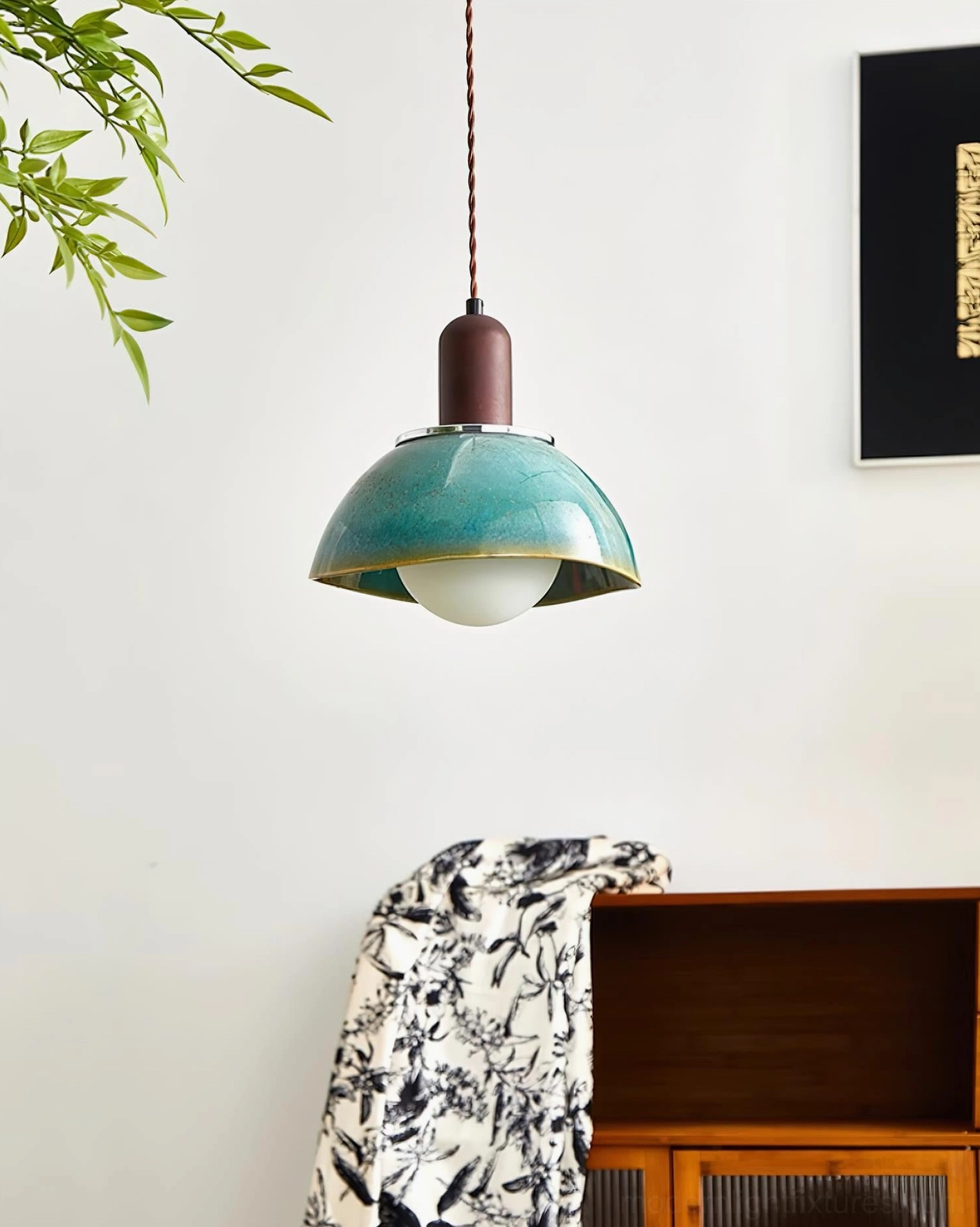 Ceramic pendant light in modern home setting with frosted bulb illuminated, side angle view above wooden cabinet