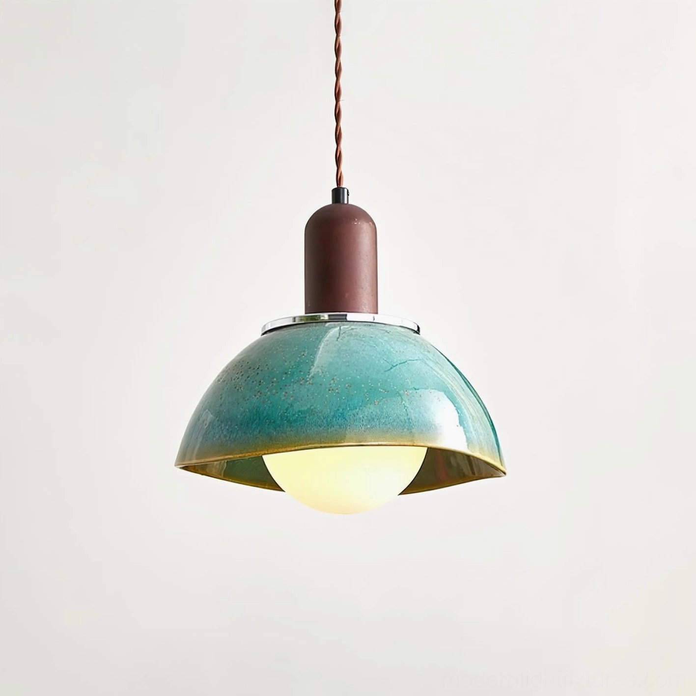 Close-up front view of Harley pendant light with illuminated frosted glass bulb and polished metal trim on ceramic shade